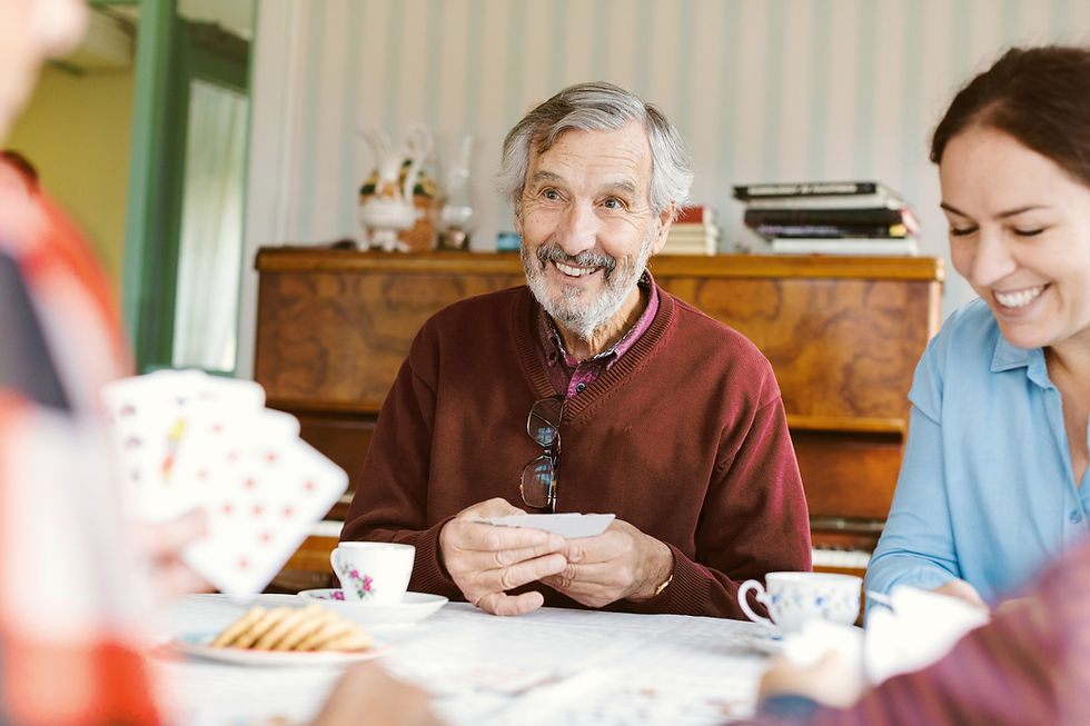 Man with greying hair playing cards with a brunette woman smiling next to him