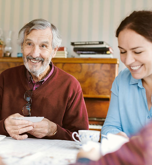 Man with greying hair playing cards with a brunette woman smiling next to him