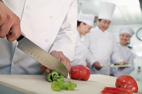Chef chopping fresh vegetables with a kitchen team in the background