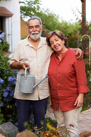 elderly-couple-holding-watering-can-while-embracing-each-other-their-countryside-home_23-2