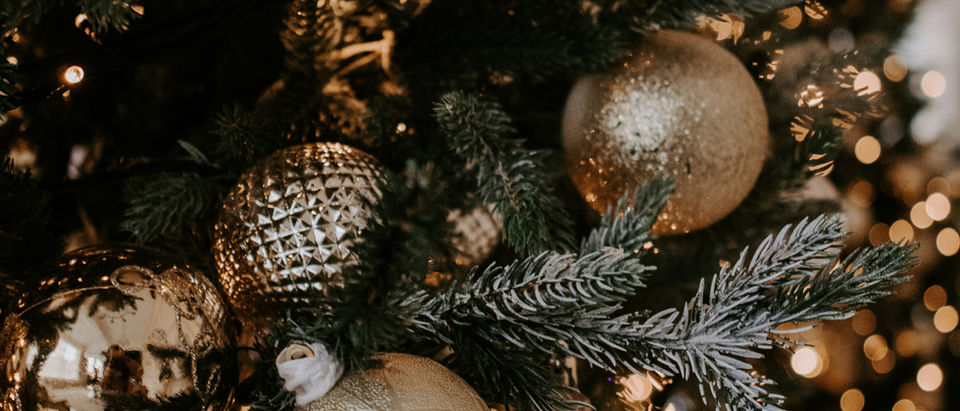Gold and champagne ornaments in several sizes hung at different depths on a lit tree