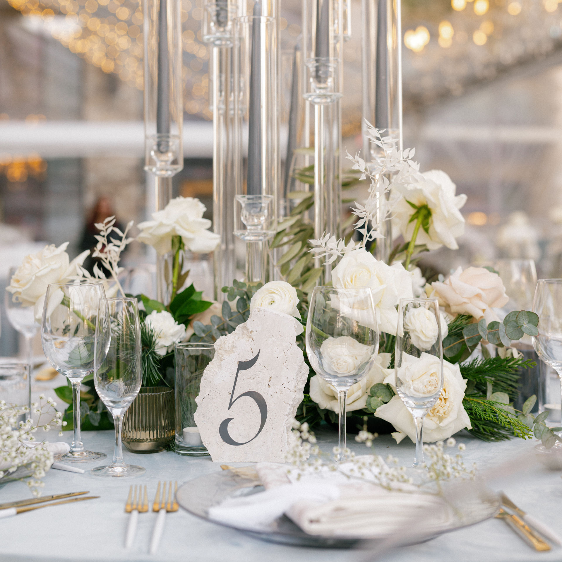 A wedding table at the St. Regis Deer Valley in Park City, Utah with a light blue velvet table cloth, candelabras, stone table numbers, and a luxury table setting