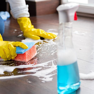 Person cleaning floor with sponge and spray bottles