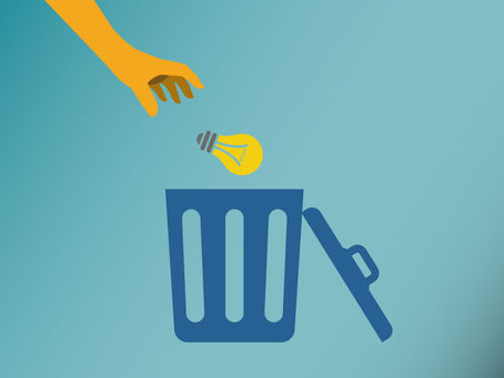 A hand throws a light bulb into a trash can