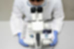 A scientist in a lab coat looks through a microscope at a magazine layout.