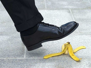 A man's foot is about to step on a banana peel