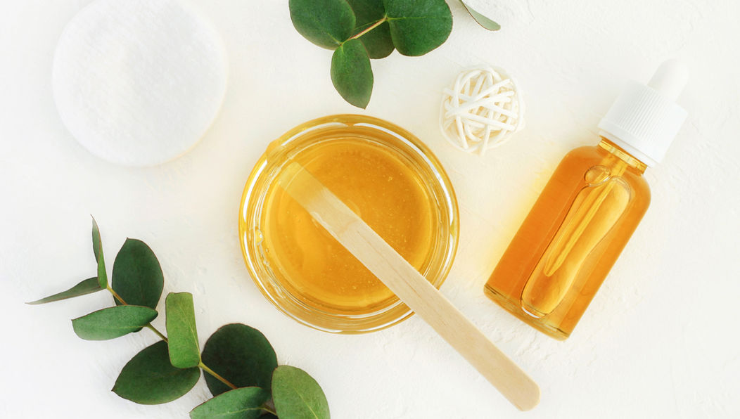 Pot met masker, olieflesje en groene bladeren