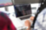 Person typing code on a laptop in a bright office. Multiple monitors display programs. The mood is focused and professional.