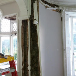 Damaged ceiling with exposed rotting wooden beam near window