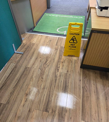 A wet floor sign is placed on the floor in a room, indicating a slippery surface for safety awareness