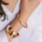 Woman's wrist wearing gold cuff bracelets