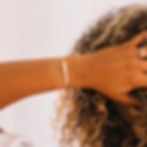 Woman's wrist wearing gold bar bracelet