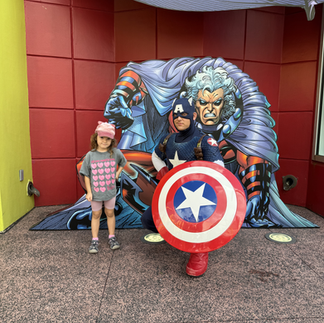 Dívka pózuje s Captainem Americou před barevnou komiksovou stěnou v části Marvel Super Hero Island.ání s hrdinou! Na Marvel Islandu jsme potkali samotného Captaina Americu – nezapomenutelný zážit