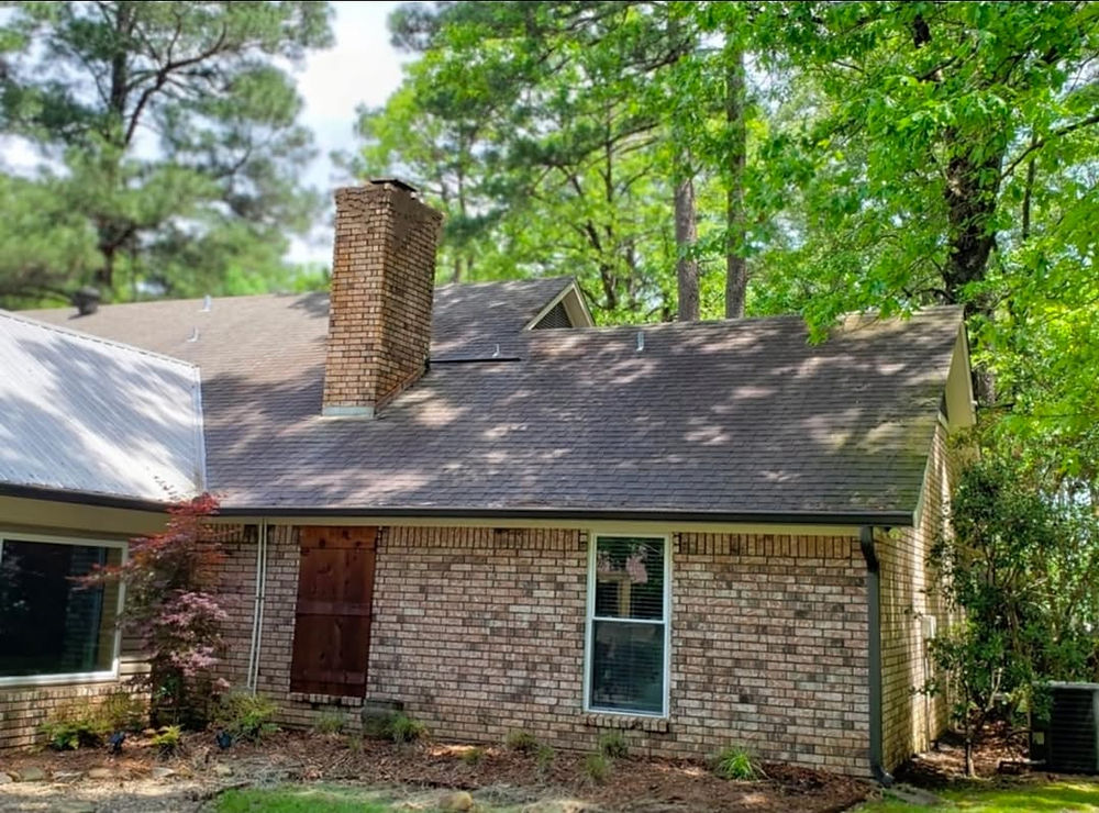 Brown brick house with chimney and green trees