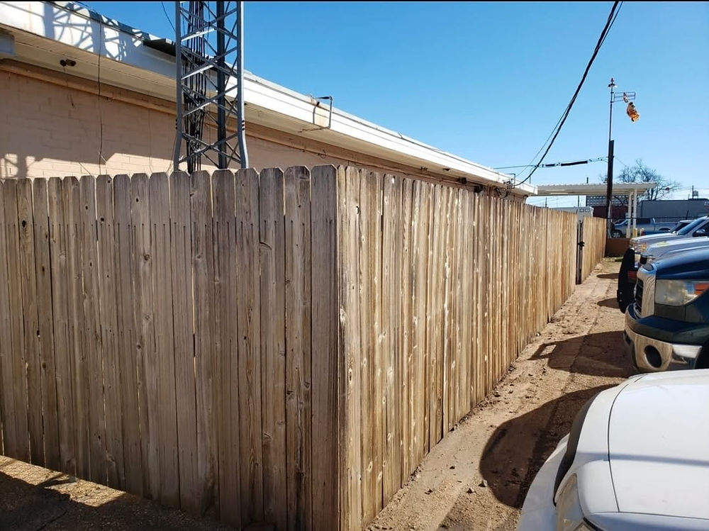 Wooden fence lining a building with parked cars