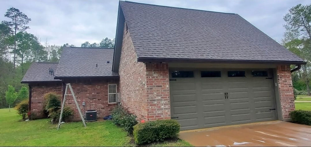 Brick house with dark roof and green garage door