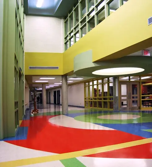 Stittsville Elementary School atrium with colourful painted walls, red, yellow, green, and blue flooring, high windows, multi-level surfaces, and complex architectural details.