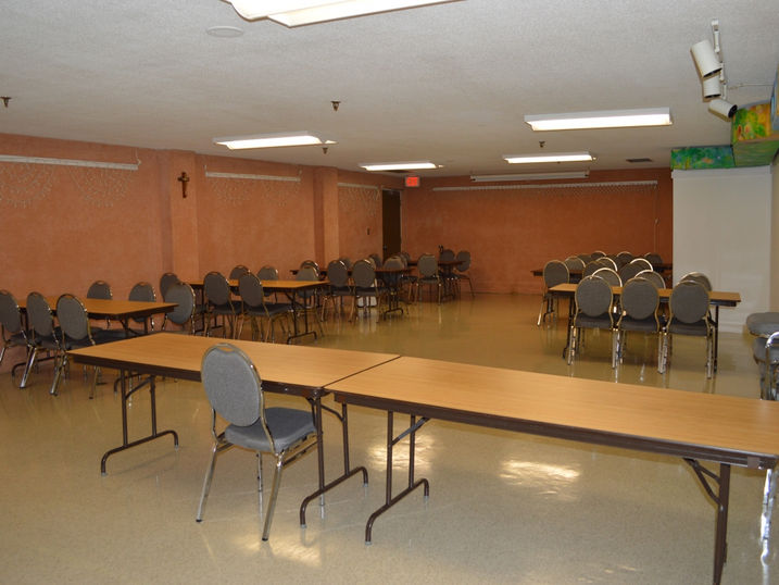 Centre J. Urgel Forget community room with freshly painted warm-toned walls, tables, chairs, ceiling lights, and open shared activity space.