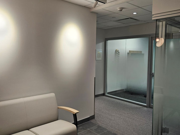 Salus Capilano waiting area with freshly painted grey walls, light seating, glass office partitions, tiled flooring, and modern overhead lighting.