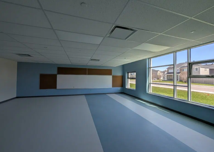 École élémentaire publique Orléans-Sud classroom with freshly painted blue accent wall, large windows, bulletin board, and clean school flooring.