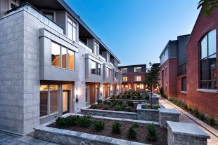 Ravenhill Common residential courtyard with modern townhome façades, large windows, landscaped walkways, and evening lighting.