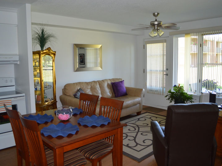 Centre J. Urgel Forget residential suite with freshly painted light walls, dining table, sofa, fireplace, ceiling fan, large windows, and warm home-style finishes.