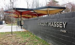 Vincent Massey Park service pavilion exterior with painted canopy structure, dark masonry wall, park signage, walkway, and surrounding trees.