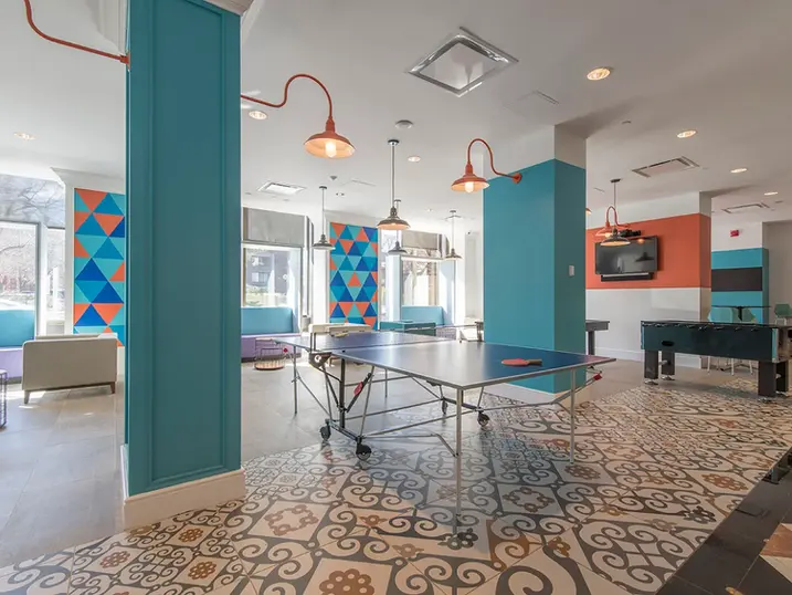 111 Cooper Street student housing lounge with freshly painted teal columns, colourful accent walls, ping pong table, seating areas, patterned flooring, and bright ceiling lights.