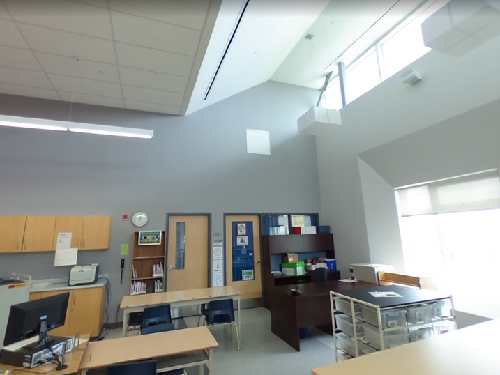 École Élémentaire Catholique Jean-Robert-Gauthier classroom with freshly painted light walls, high windows, cabinets, desks, storage shelves, and bright ceiling lighting.