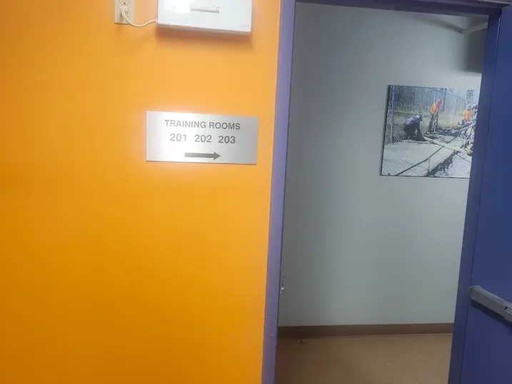 LiUNA Local 527 training room entrance with freshly painted orange accent wall, blue door frame, training room sign, corridor opening, and interior wall finishes.