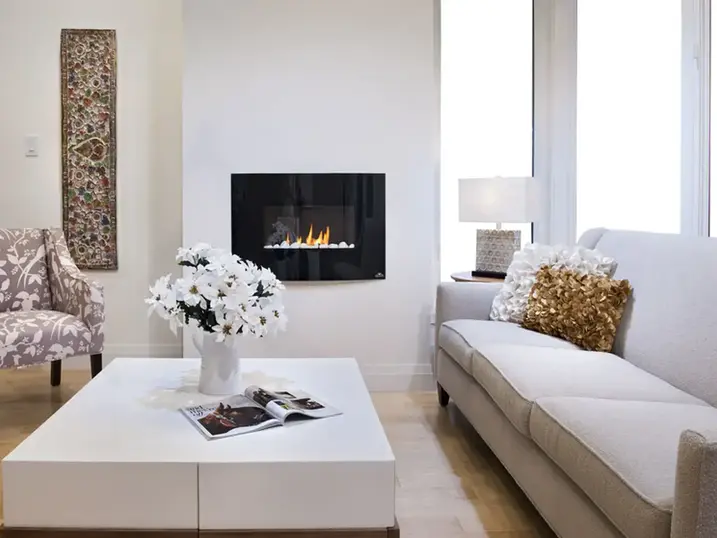 Ravenhill Common living room with freshly painted white walls, sofa, fireplace, coffee table, large window, and light wood flooring.