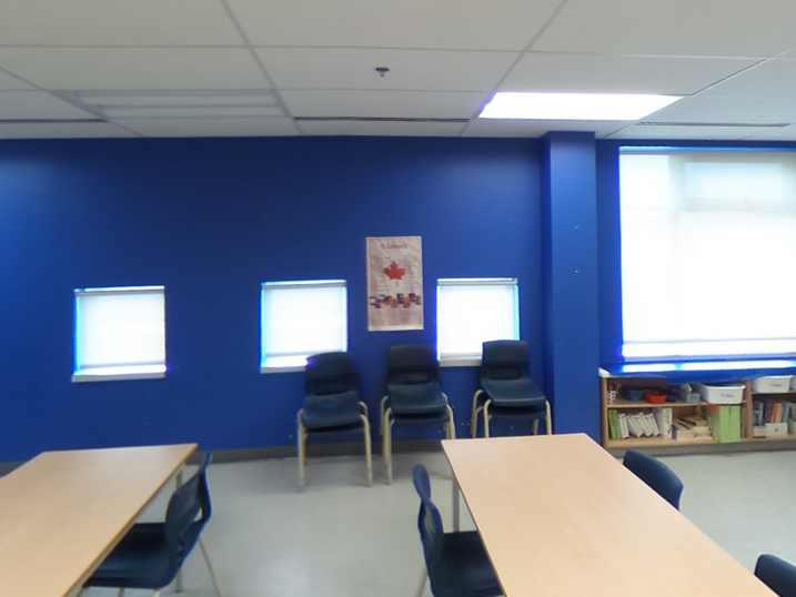 École Élémentaire Catholique Jean-Robert-Gauthier classroom with freshly painted blue accent wall, study tables, chairs, bulletin board, small windows, and bright ceiling lights.