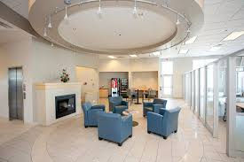Hunt Club Honda customer lounge with freshly painted light walls, circular ceiling detail, fireplace, blue chairs, tiled flooring, and glass partitions.