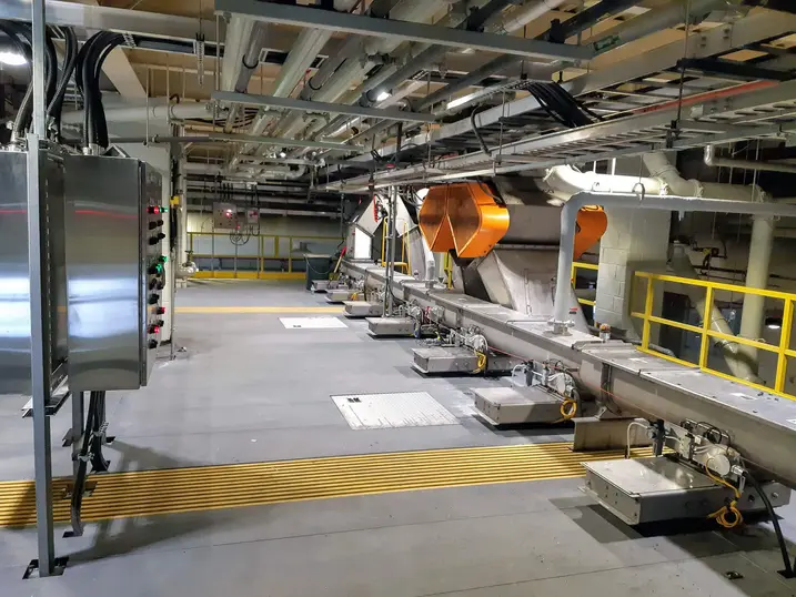 ROPEC industrial service area with painted concrete floor, exposed piping, control panel, safety railings, equipment platforms, and technical mechanical systems.
