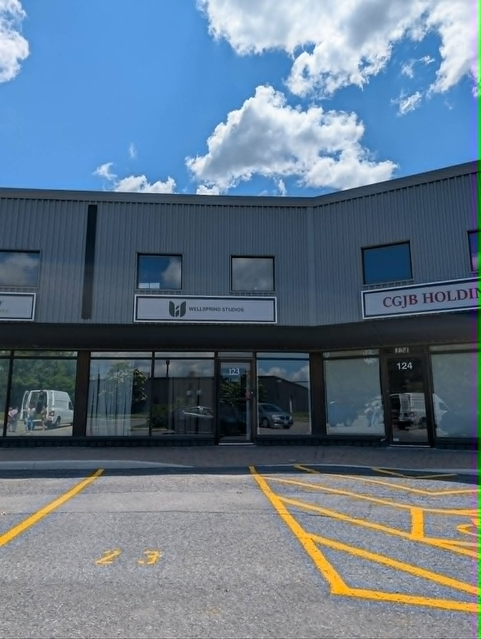 Commercial warehouse painting project by Vision Painting at Wellspring Studios in Nepean, Ontario, featuring an exterior storefront and interior studio space with freshly painted black ceilings, white and black walls, doors, trims, exposed structure, ductwork and professional spray-applied finishes.