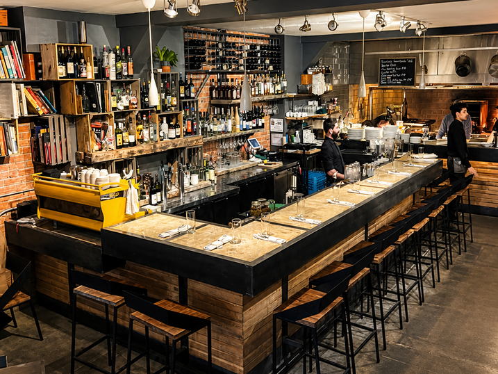 Montfort Renaissance restaurant interior with freshly painted dark accent walls, bar seating, dining tables, shelves, pendant lighting, and warm interior finishes.
