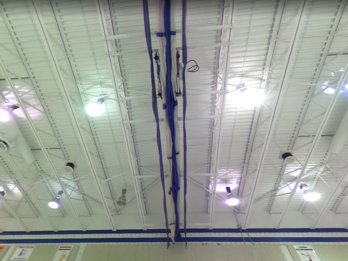 Renovated school ceiling with a white painted steel deck, suspended light fixtures, and visible ducts.