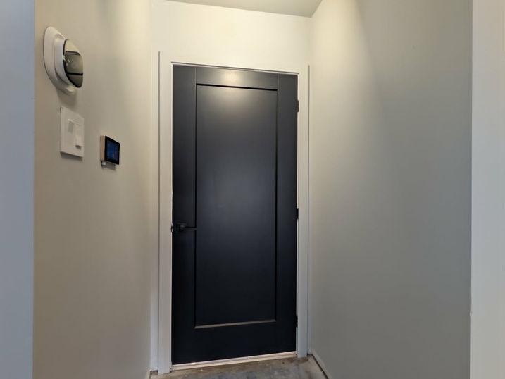 Interior commercial painting at Wellspring Studios in Nepean, Ontario, showing a freshly painted entry area with light walls, white trim, dark interior door, ceiling detail and concrete floor.