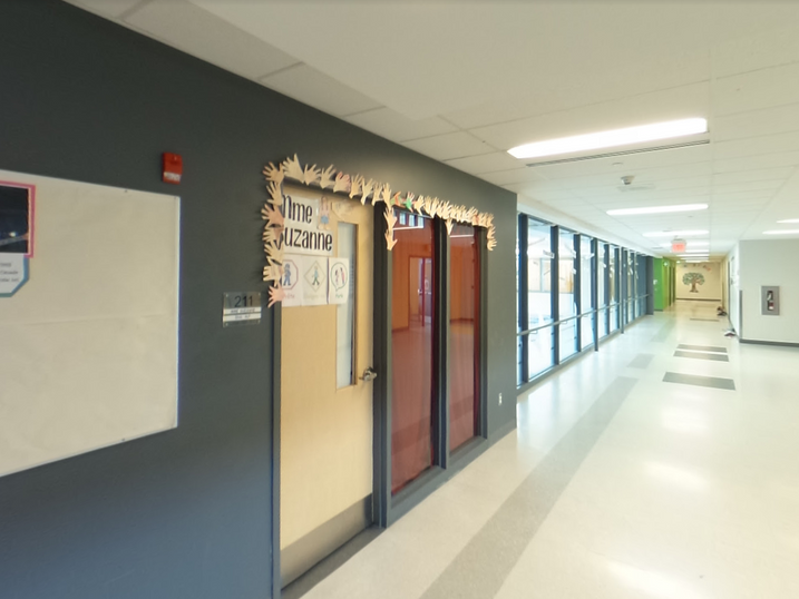 École Élémentaire Catholique Jean-Robert-Gauthier corridor with freshly painted accent walls, classroom doors, bulletin board, glass partitions, light flooring, and bright ceiling lights.