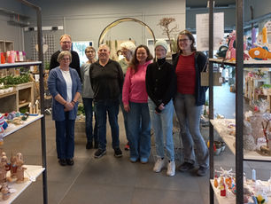 8 Menschen stehen zusammen zu einem Gruppenfoto. Links und rechts sind die gefüllten Kreativregale zu erkennen.