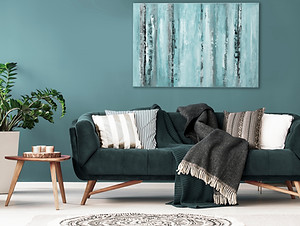 Patterned cushions on sofa next to wooden table and plant in dark apartment interior Real