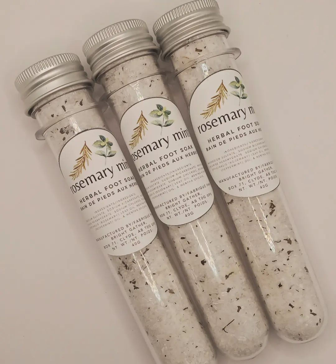 3 clear vials with grey metal lids and white labels. The contents of the vials is a white and green mixture of salts and herbs and makes up the Herbal Foot Soak