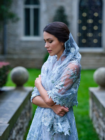 portrait of woman in sleeveless dove grey embroidered mother of the groom gown with veil in garden