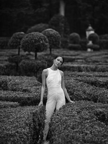 woman in white beaded cutaway jumpsuit posing in garden