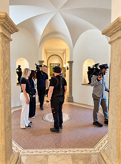 Libby Barnes and Leon with the Ranchland Listings camera crew inside a vaulted entry with stone columns and a mosaic floor
