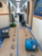 Eye-level view of a professional air mover drying a carpeted floor