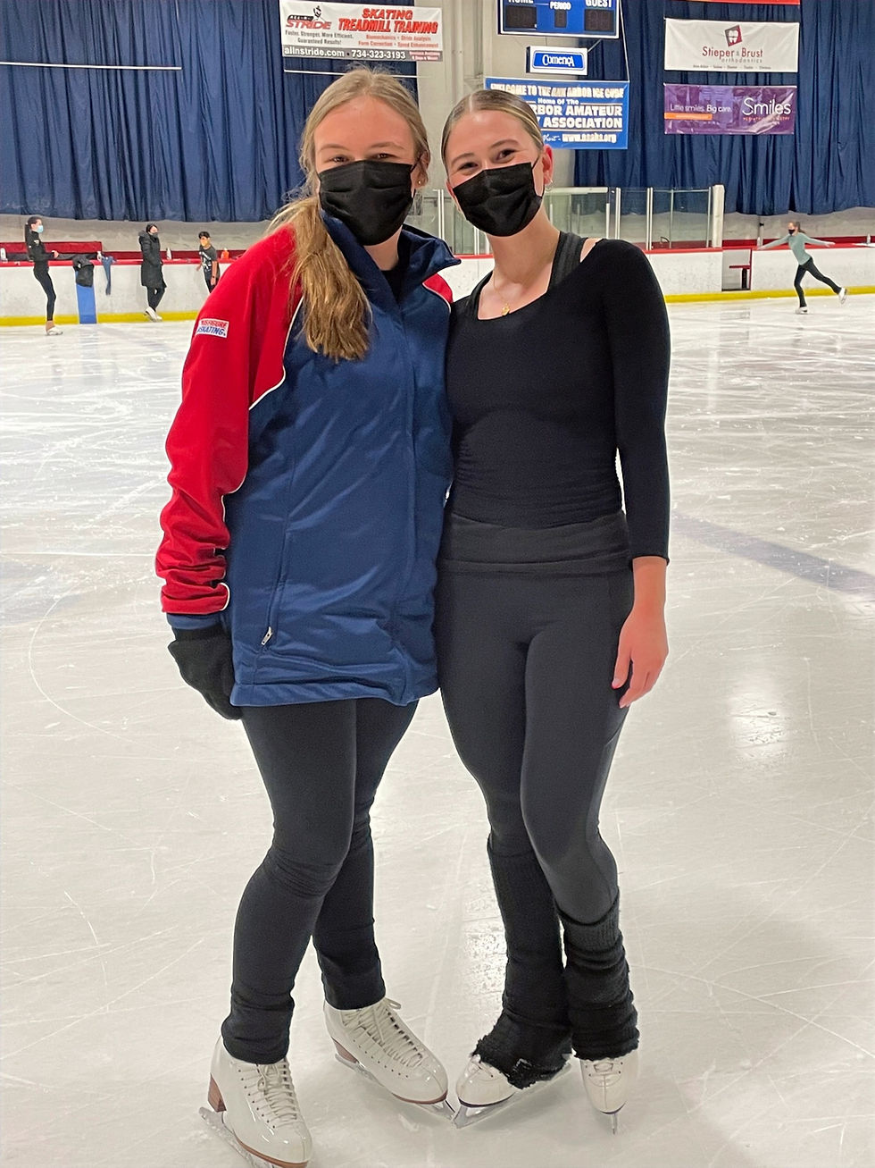 Grace and Emma, two young women, side hug on the rink.