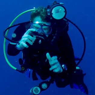 Greg Cooley under water wearing scuba gear.