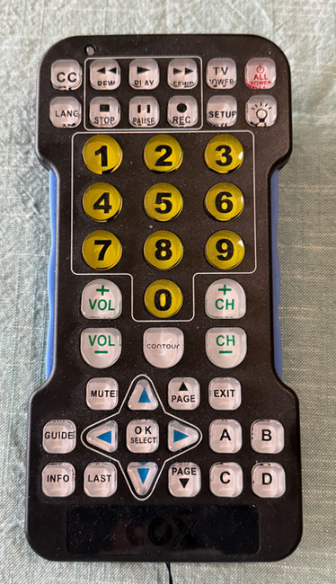 A black TV remote control with raised, large buttons designed for people with visual disabilities. 