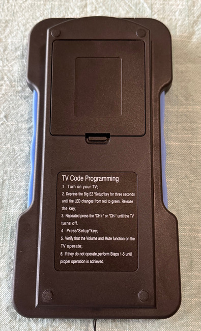 The back of a black TV remote control with programming directions is small text.